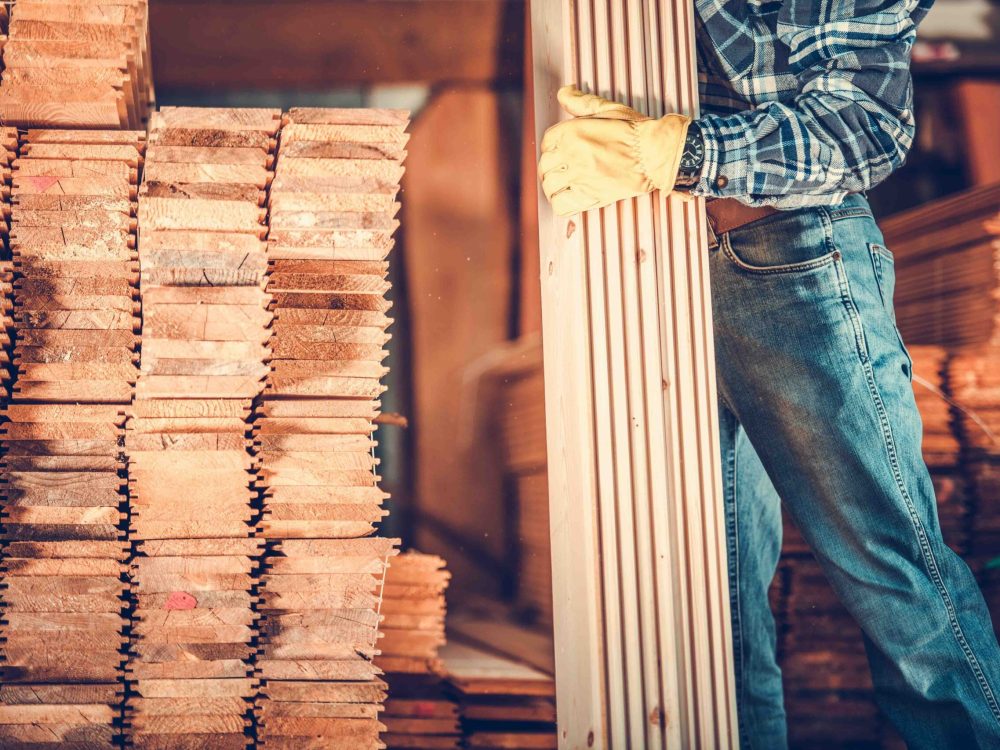 Contractor with Planks. Caucasian Carpenter with Pile of Wood Boards. Construction Materials Theme.